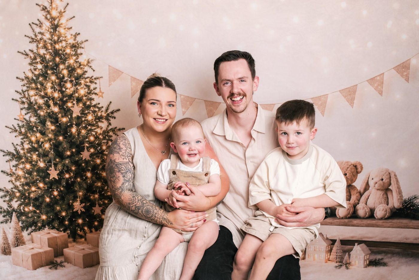 A family smiling together beside the Christmas tree