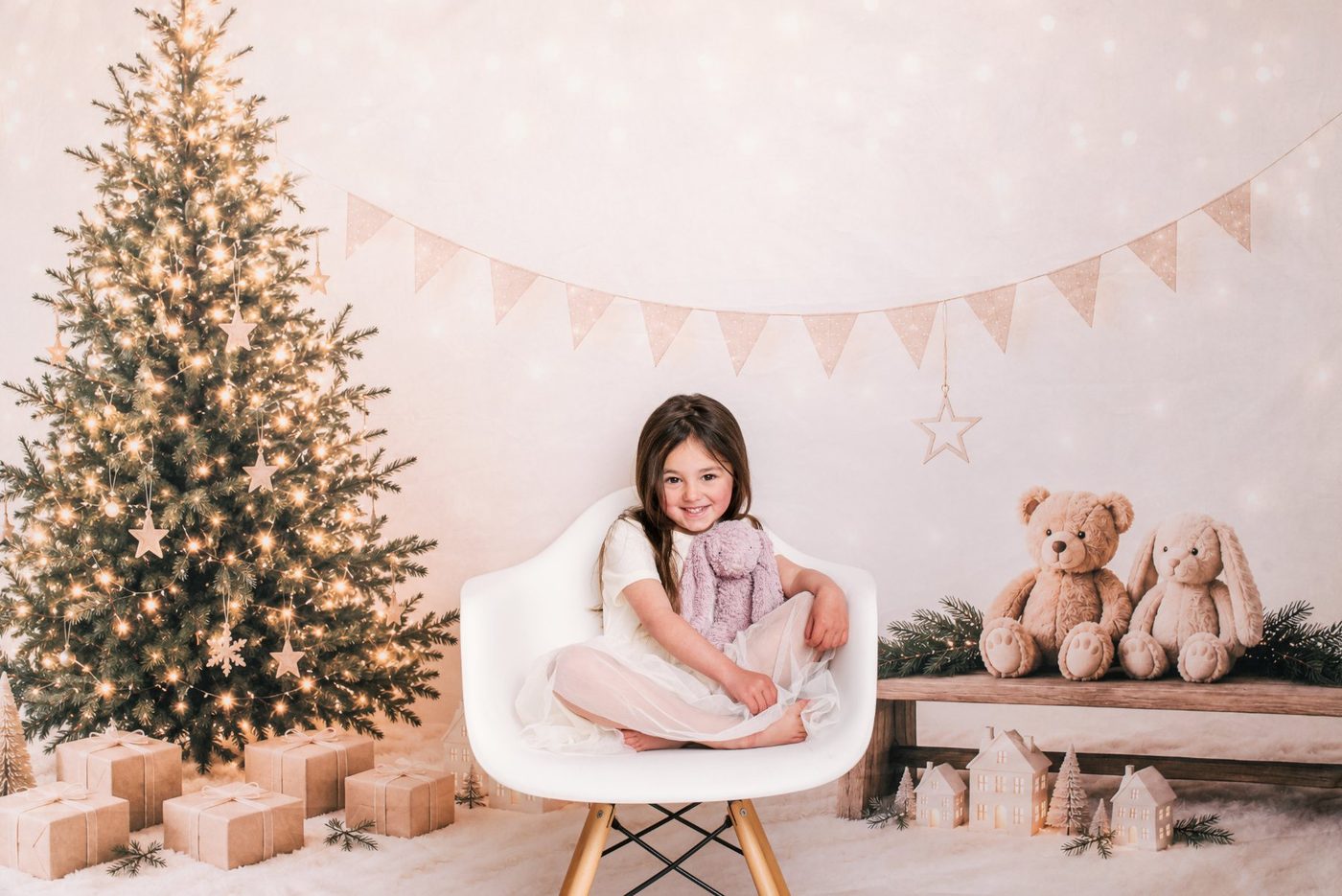 A little girl on the white chair beside the Christmas tree