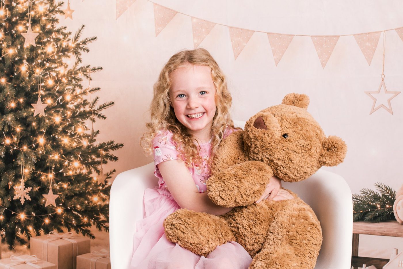 A little girl hugging a big teddy bear on the Christmas set
