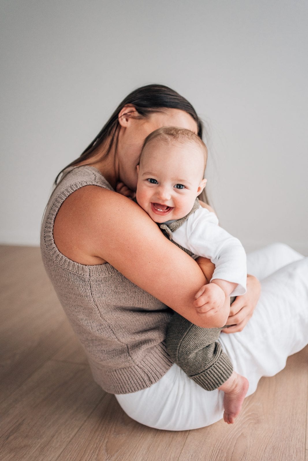 Mother cuddling her smiling baby during a natural-light Studio Story session at The Little White Studio in Lincoln