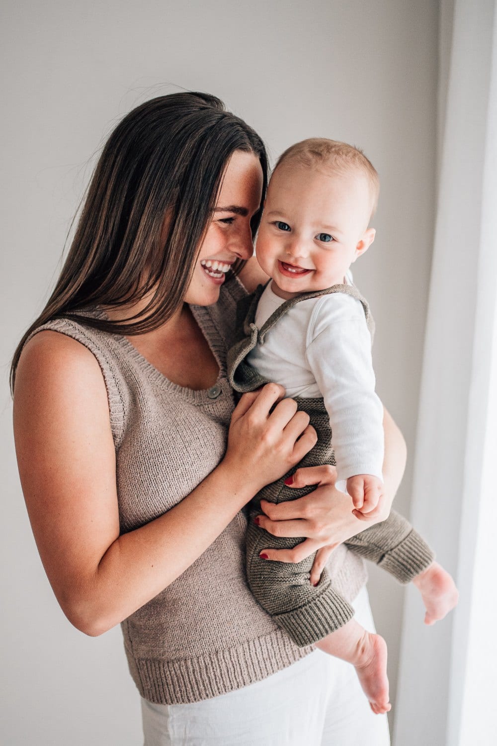 A mother laughing with her baby during a natural-light studio session