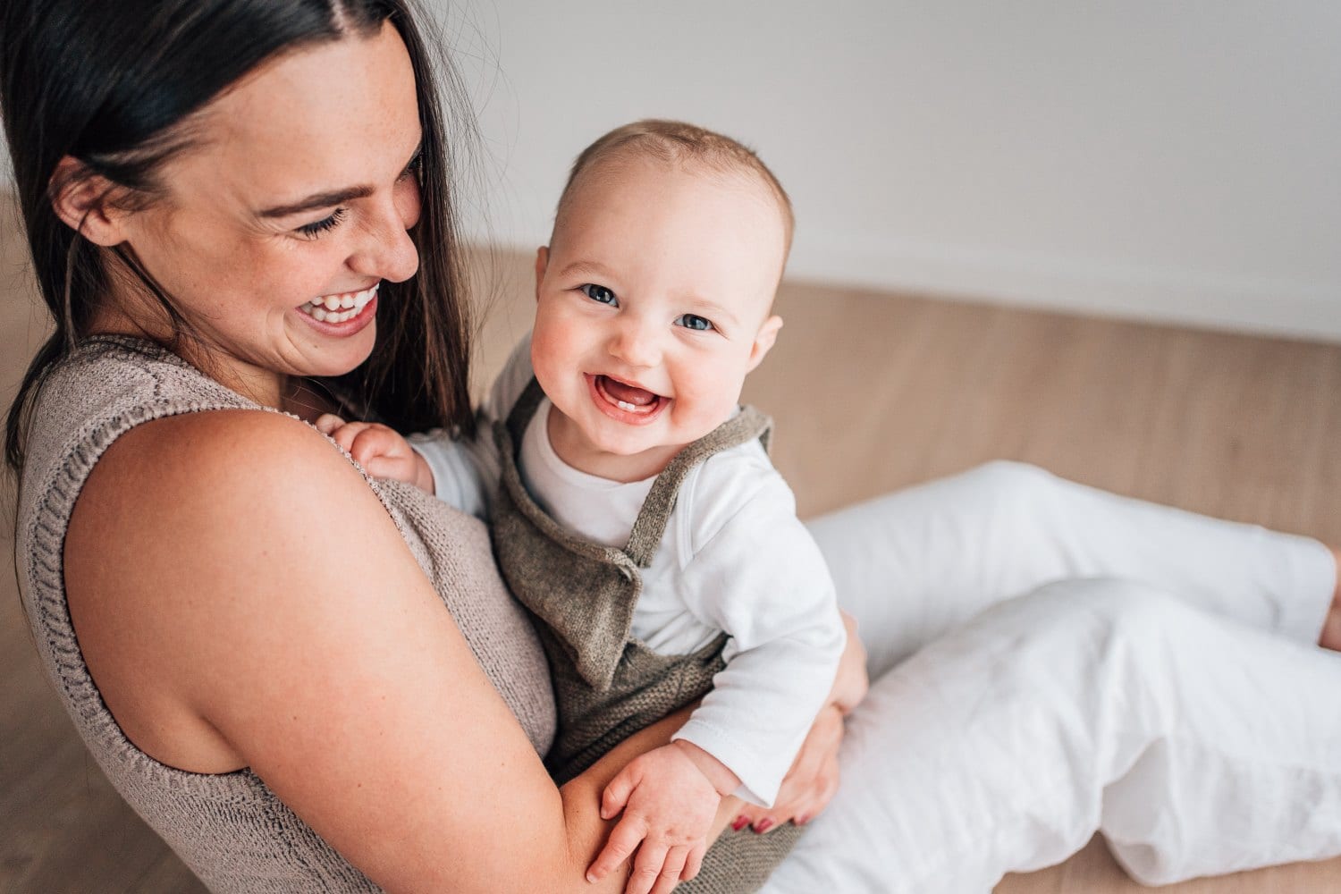 A mother laughing with her smiling baby during a studio session