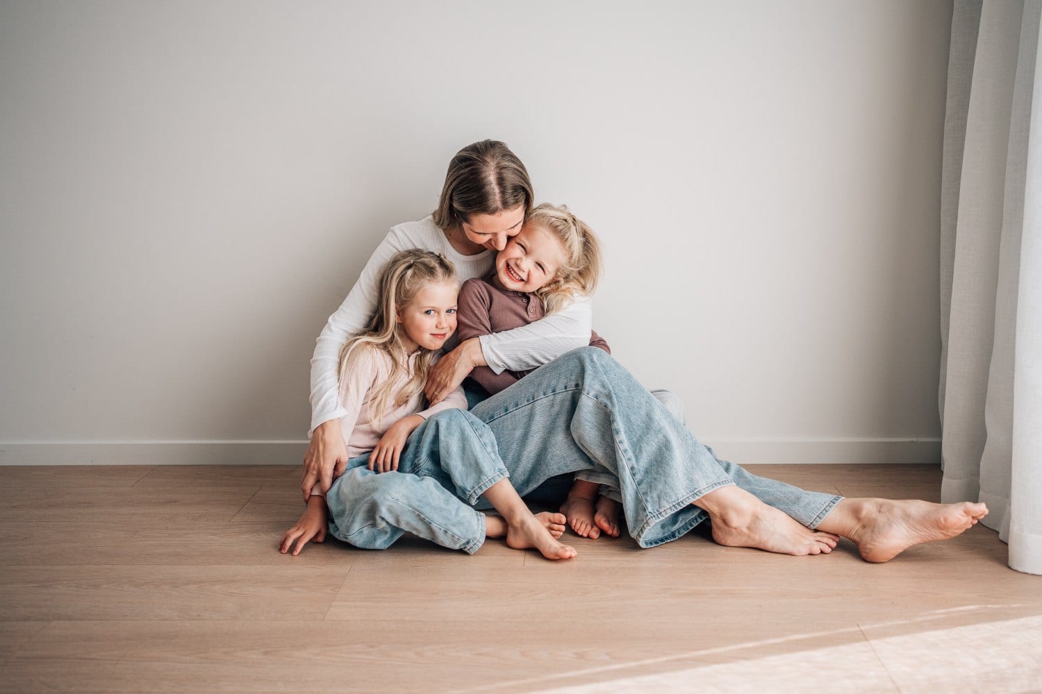 A mother and her two girls cuddled together on the studio floor