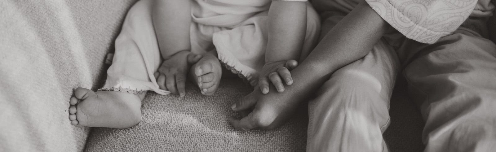 Black and white detail of two siblings' hands and feet during a studio session