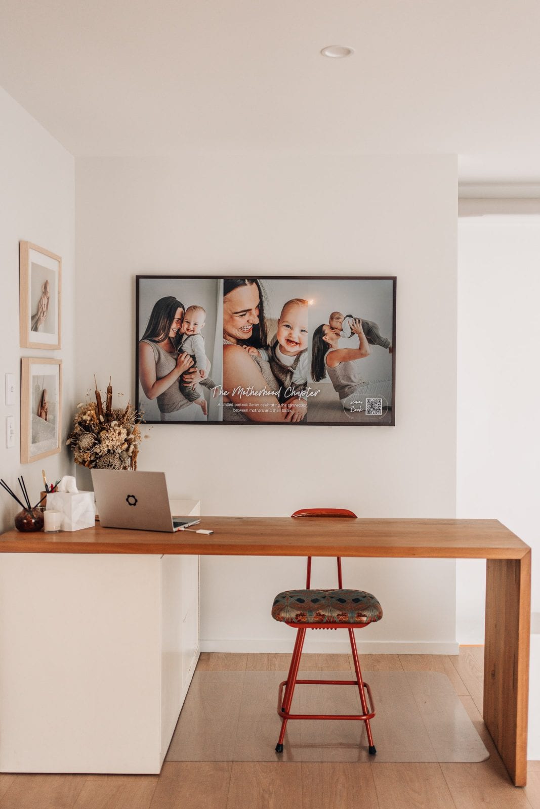 Timber consultation desk beneath a framed motherhood print in the airy viewing space of our Lincoln, Canterbury family portrait studio.