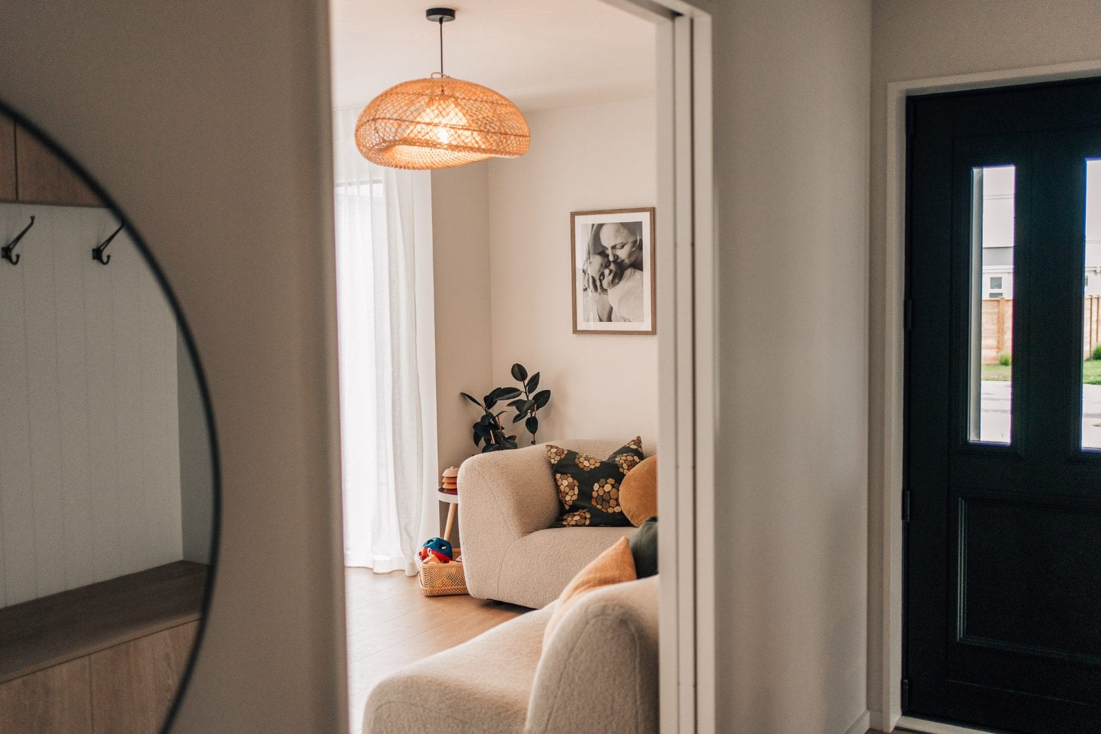 Round entry mirror reflecting the coat hooks with a view through to the lounge at our Lincoln, Canterbury portrait studio.