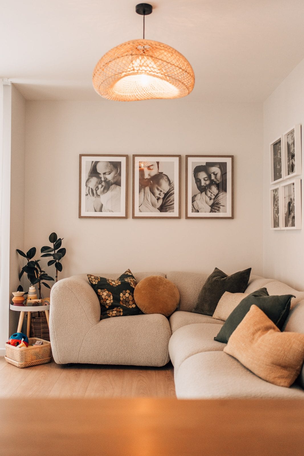 Boucle sofa beneath a newborn portrait triptych in the warmly lit lounge of our Lincoln, Canterbury family portrait studio.