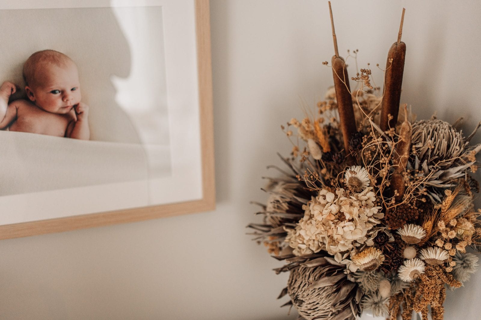 Framed newborn portrait beside a dried native flower arrangement at our Lincoln, Canterbury newborn and family portrait studio.