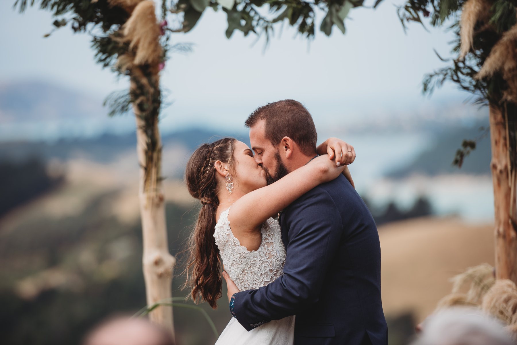 A couple sharing their first kiss under a ceremony arch