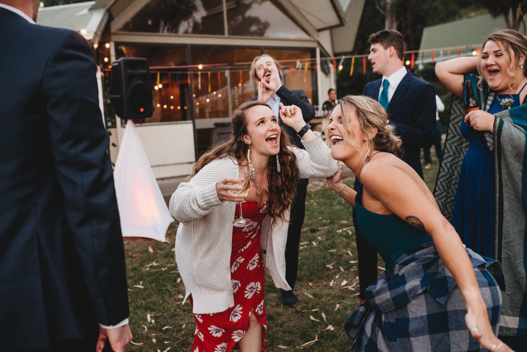 Guests singing and dancing together on the lawn at the reception