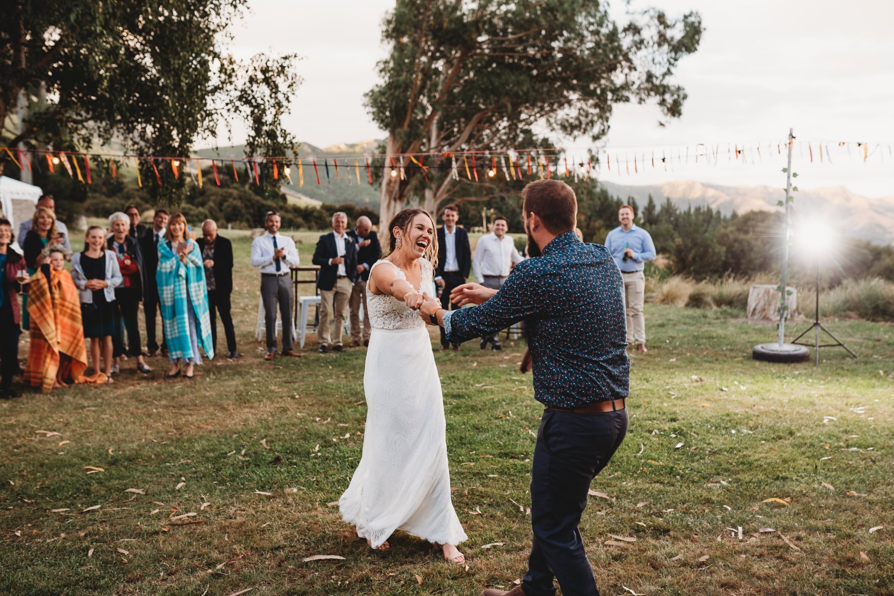 A couple laughing through their first dance on the lawn