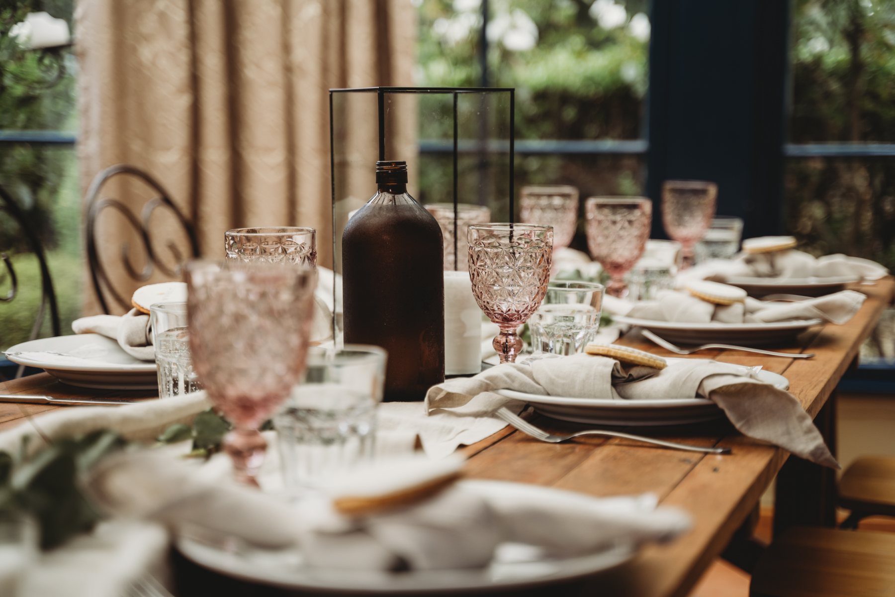 Pink crystal glasses and linen napkins on a long timber table