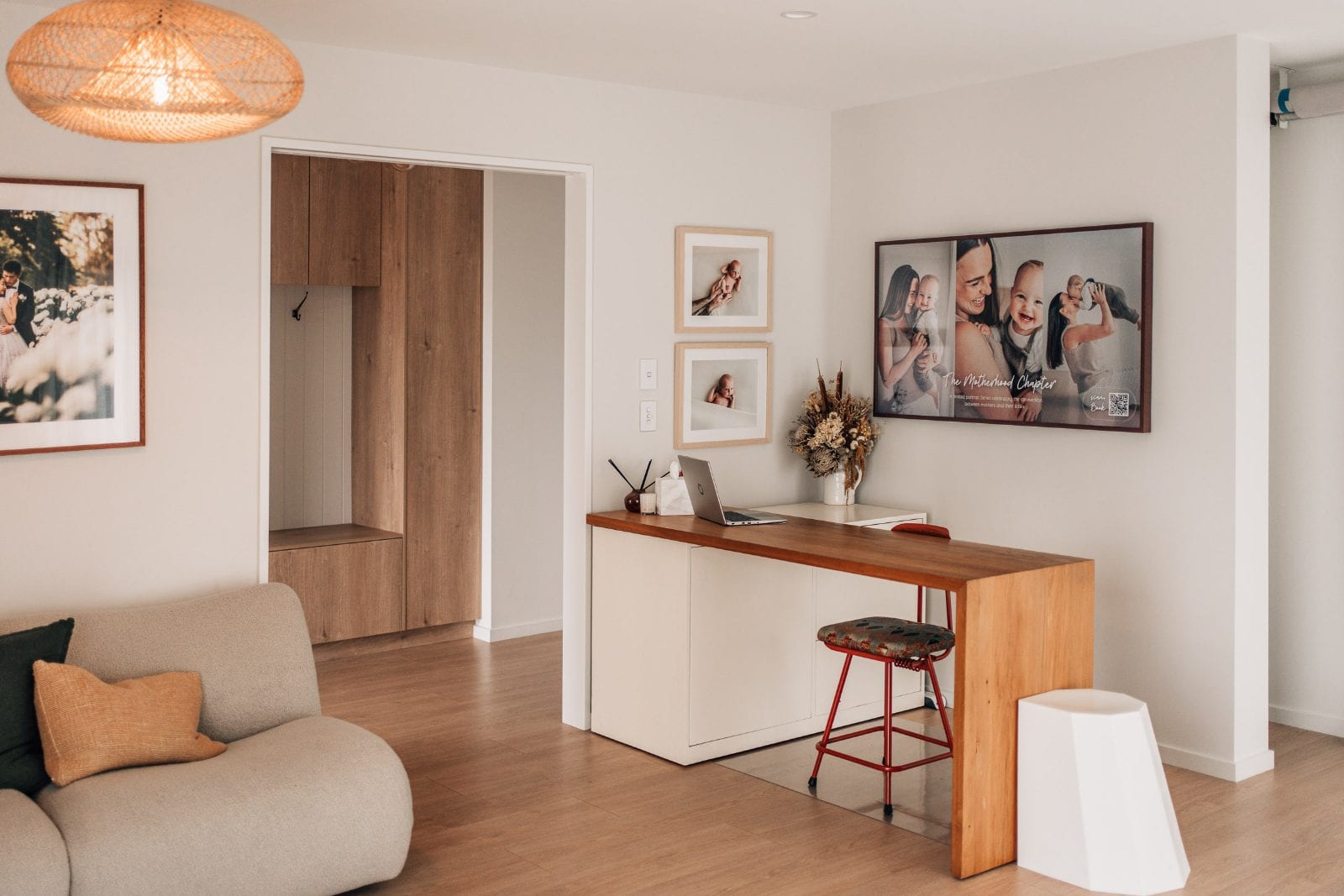 Bright studio lounge with a timber consultation desk, framed newborn portraits and a woven pendant light at our Lincoln, Canterbury portrait studio.